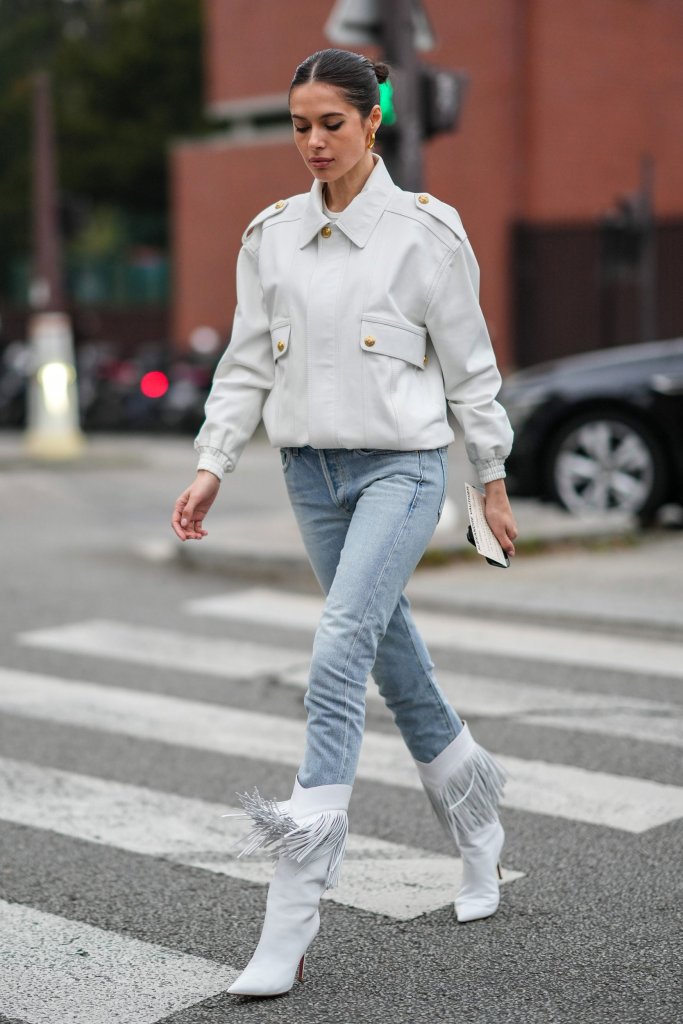 Girl walking in jeans, white boots and jacket for best jeans for body shape